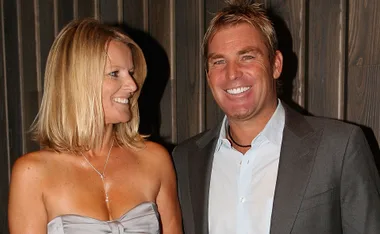 A man and woman smiling together, with the woman in a strapless dress and the man in a suit.
