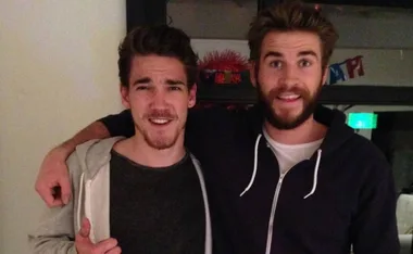 Two smiling men with short hair and beards, one in a gray shirt and hoodie, the other in a black zip-up hoodie.