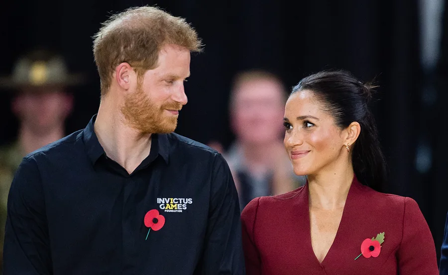Prince Harry and Meghan Markle smiling at each other at the Invictus Games.