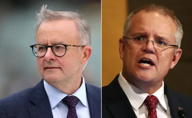 Two politicians in suits; one in glasses looking aside, the other speaking with an open mouth.