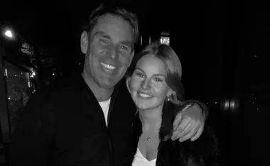 A black and white photo of a smiling man and woman embracing in a dimly lit setting.