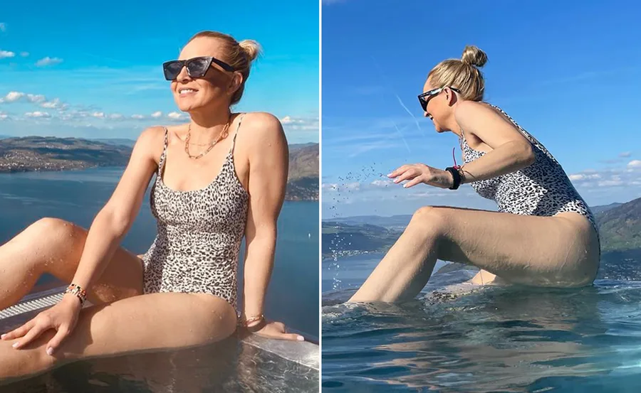 Woman in leopard print swimsuit enjoys sunny day by pool with scenic mountain and lake views.
