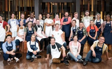 Group of people wearing aprons, smiling in a kitchen setting.