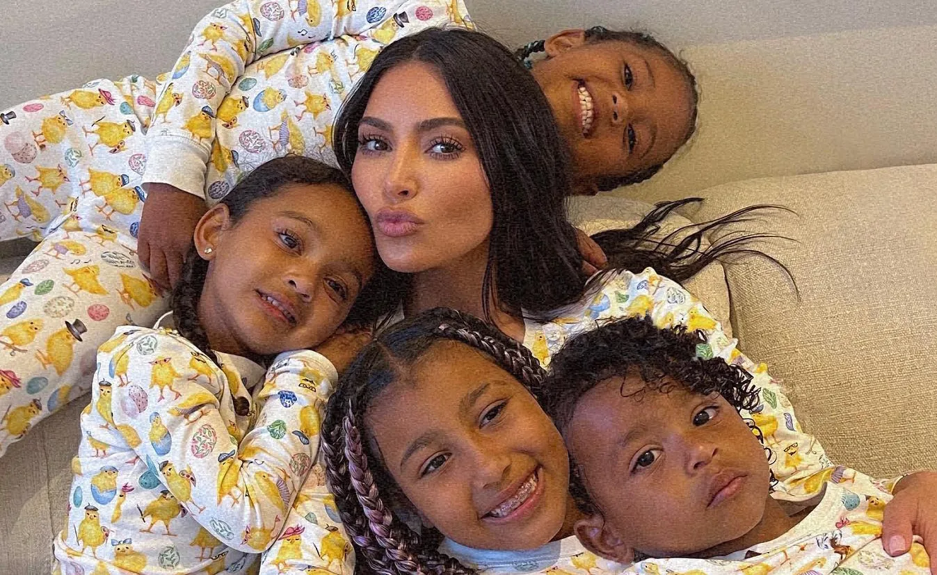Celebrity with four children in matching pajamas on a couch, smiling and relaxed together.