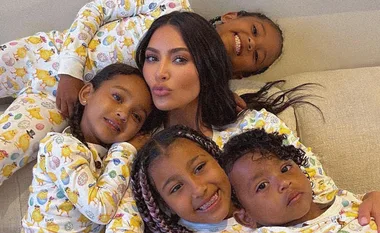 Celebrity with four children in matching pajamas on a couch, smiling and relaxed together.