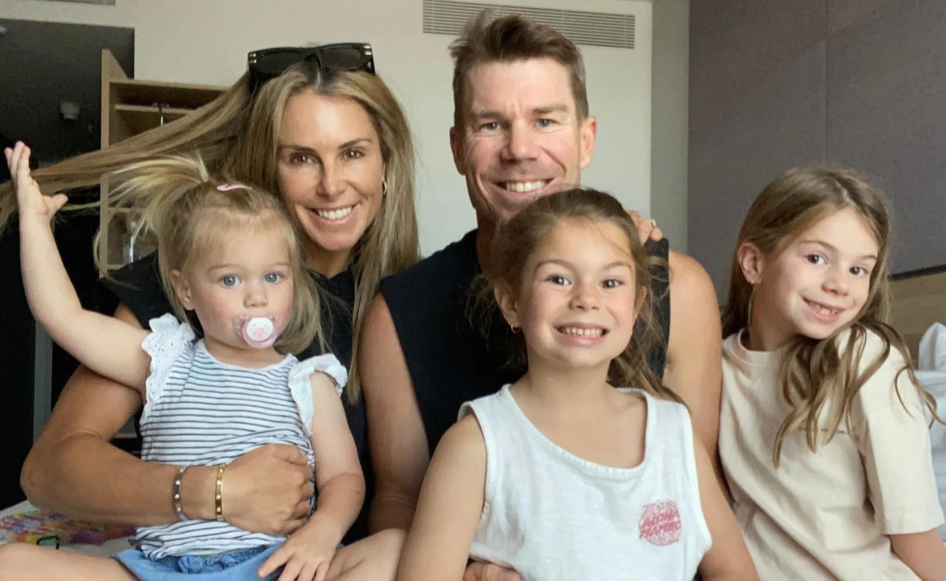 A happy family posing together indoors, smiling at the camera.