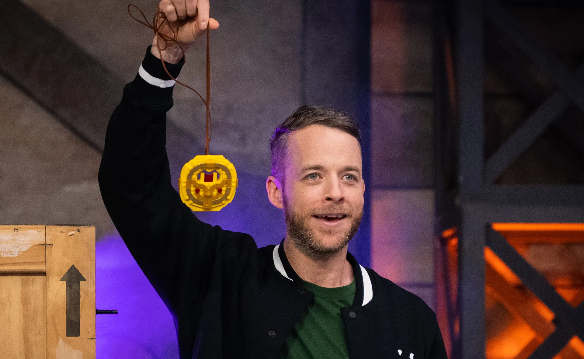 A person holding a LEGO trophy on a stage, looking happy and excited.