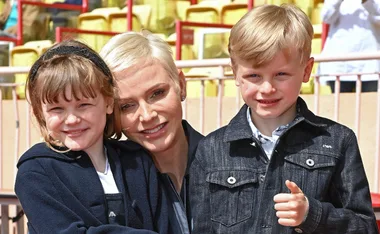 Princess Charlene with twins smiling at an outdoor event.
