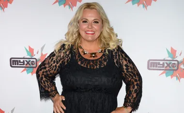 Blonde woman in a black lace dress smiling at a Myx TV event.