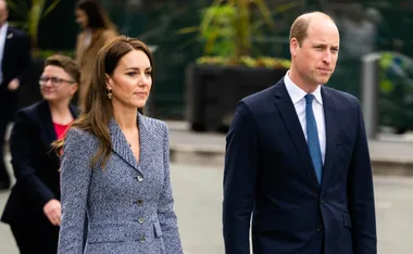 Prince William and Kate Middleton walking in formal attire during a visit to Manchester.