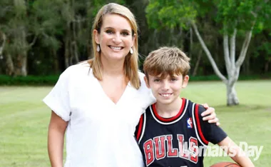 Woman in a white top with a young boy in a Bulls jersey, smiling outdoors; trees in the background.
