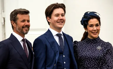 Three people smiling, dressed in formal attire, with a white background.