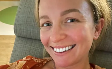 Woman smiling close-up while sitting in a hospital chair.
