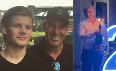 Group photo at tennis match; young man with champagne and sparklers celebrating, wearing a white shirt.