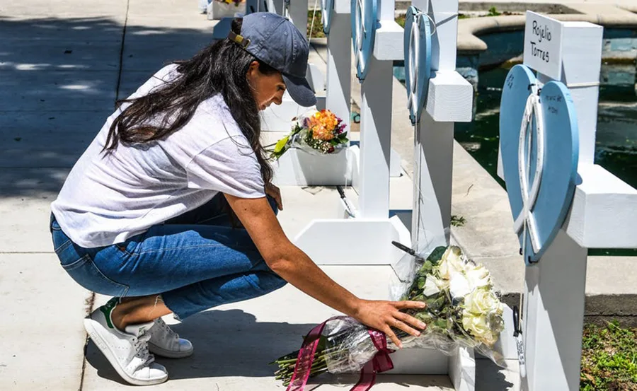 Woman placing flowers at memorial crosses in Texas.