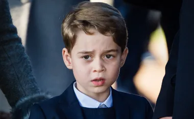 ```html
<img src="https://dfa.com.au/wp-content/uploads/2018/09/Prince-George.jpg" alt="Young boy in a suit with brown hair, looking serious." />
```