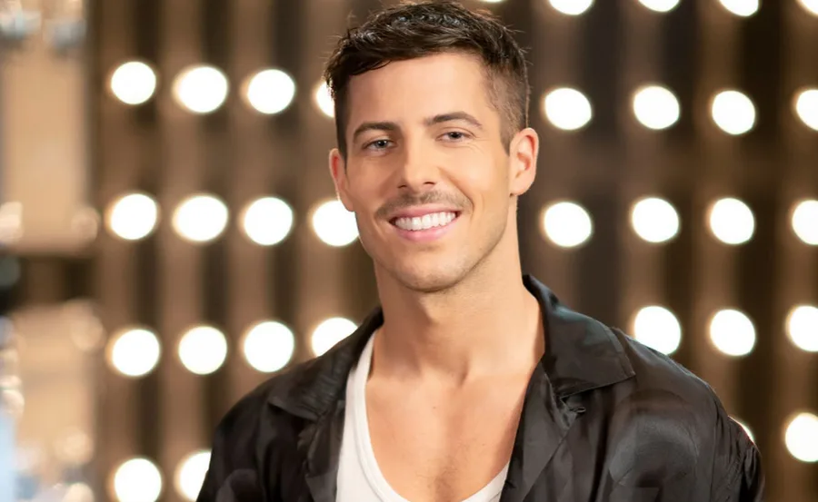 Smiling man with short hair against a backdrop of circular lights.