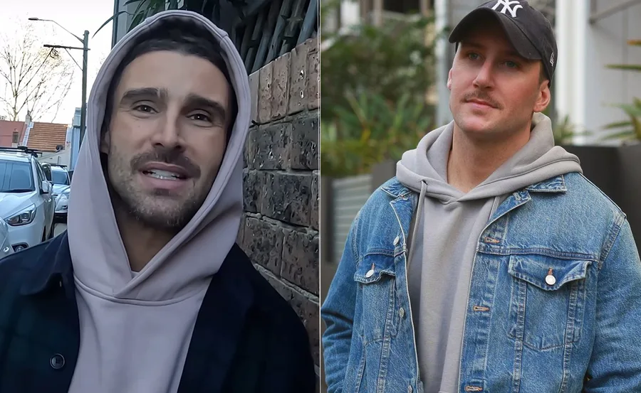 Two men outdoors wearing casual hoodies and jackets; one with a cap and the other with a hood up.