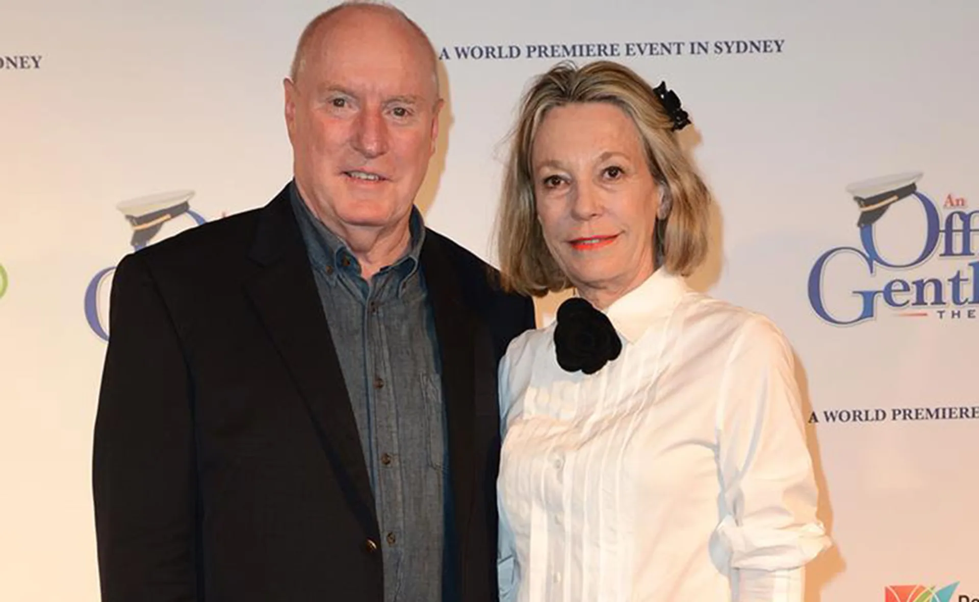 Couple attending a premiere event in Sydney, posing on the red carpet with a backdrop displaying event details.