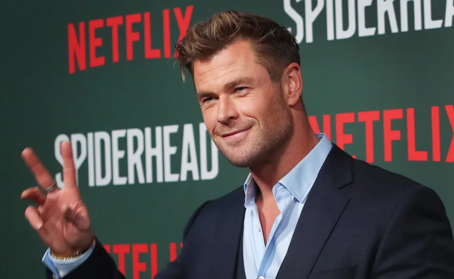 Actor at a Netflix Spiderhead event, wearing a suit and gesturing a peace sign.