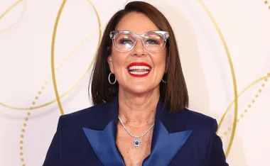Person smiling in glasses, wearing a blue outfit and a necklace, at the 2022 Logie Awards.