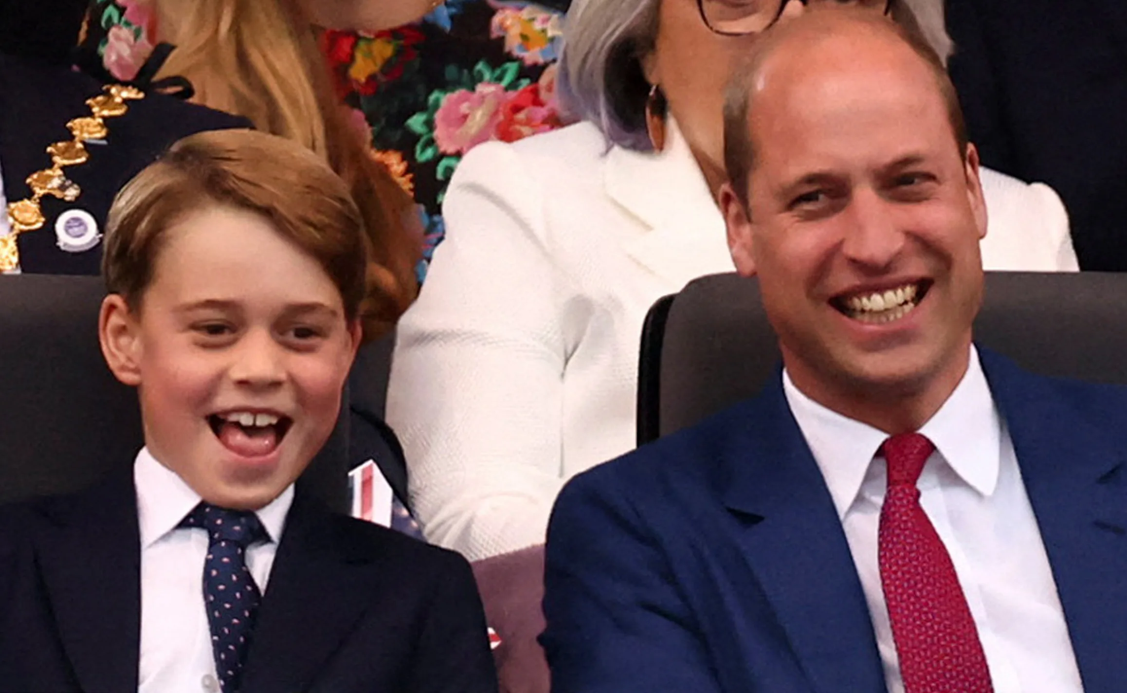 Father and son laughing together at an event, dressed in formal attire.