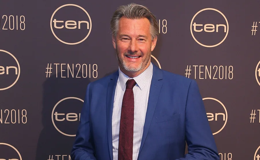 Man in a blue suit smiles at a TEN2018 event backdrop.