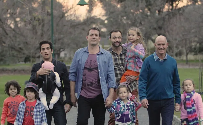 A group of diverse fathers and children walking together in a park setting.