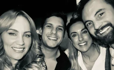 Four people smiling closely together in a black and white photo.