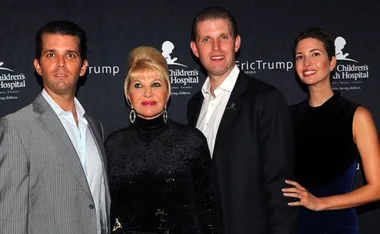 A group of four individuals posing together at a charity event backdrop.