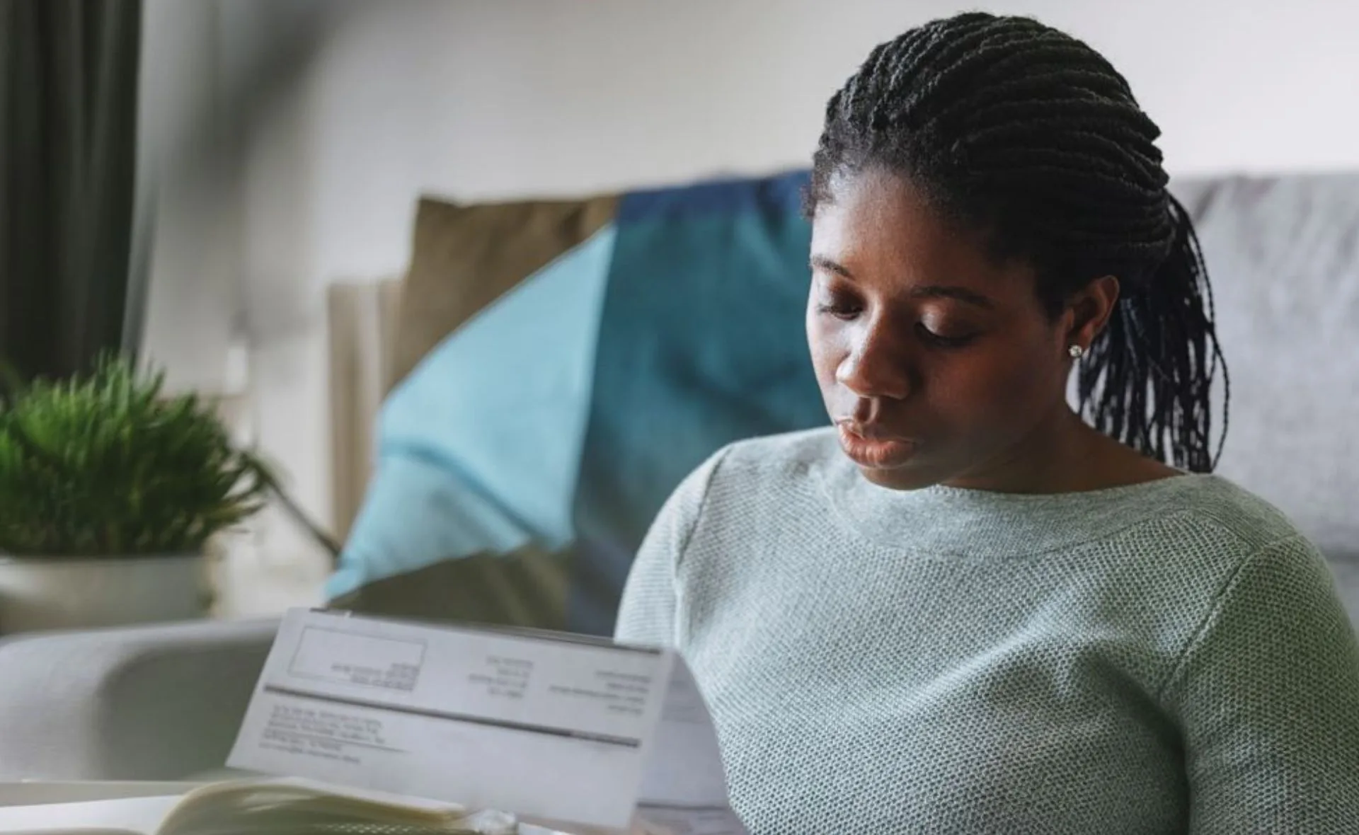 Woman reading a bill at home with a thoughtful expression.