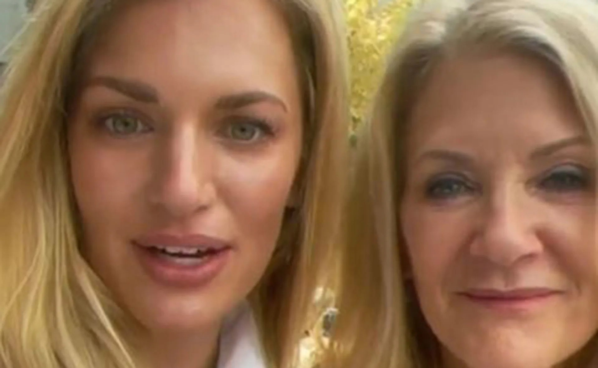 Two women with long blonde hair smiling at the camera with an autumnal background.