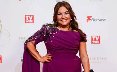 Actress in a purple dress with embellished shoulder, smiling at a TV Week event.