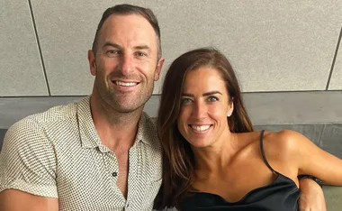 A couple smiling and posing closely together against a neutral background.