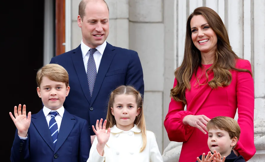 A family of five smiling and waving on a balcony, with three children in front.