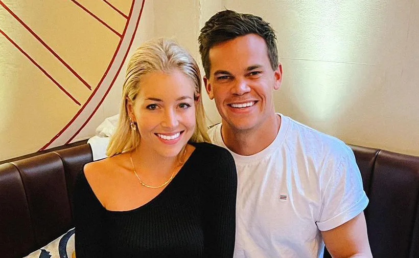 Couple smiling and sitting together indoors, woman in black top, man in white shirt.