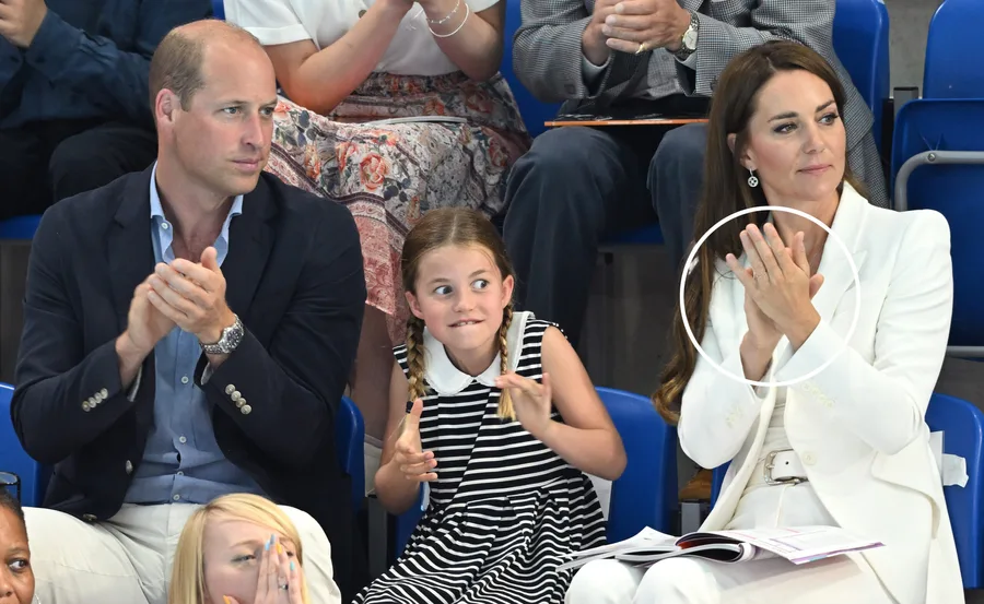 A family applauding at a sports event; woman in white suit has a ring circled for emphasis.