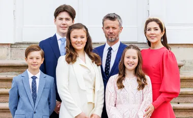 A family of six posing on stairs, adults in formal attire, three children in suits and dresses, smiling at the camera.