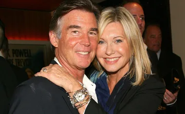Couple smiling and embracing at an event, with the woman wearing a watch and bracelets.