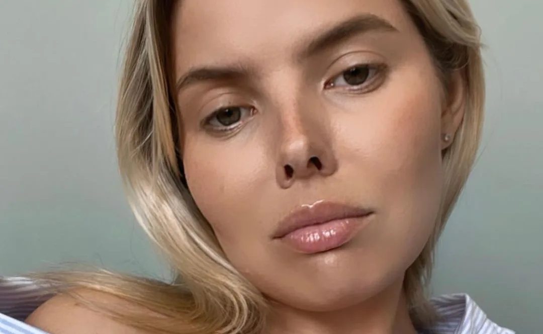 Alt text: Close-up of a woman with blonde hair, looking directly at the camera with a neutral expression.
