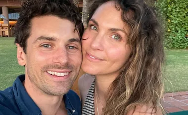 Selfie of a smiling couple outdoors, with greenery in the background.
