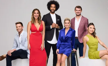 Group of six well-dressed people posing against a gray background.