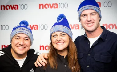 Group smiling in blue beanies at Nova 100 backdrop.