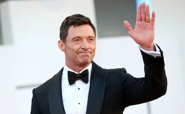 Man in a tuxedo waving at an event.
