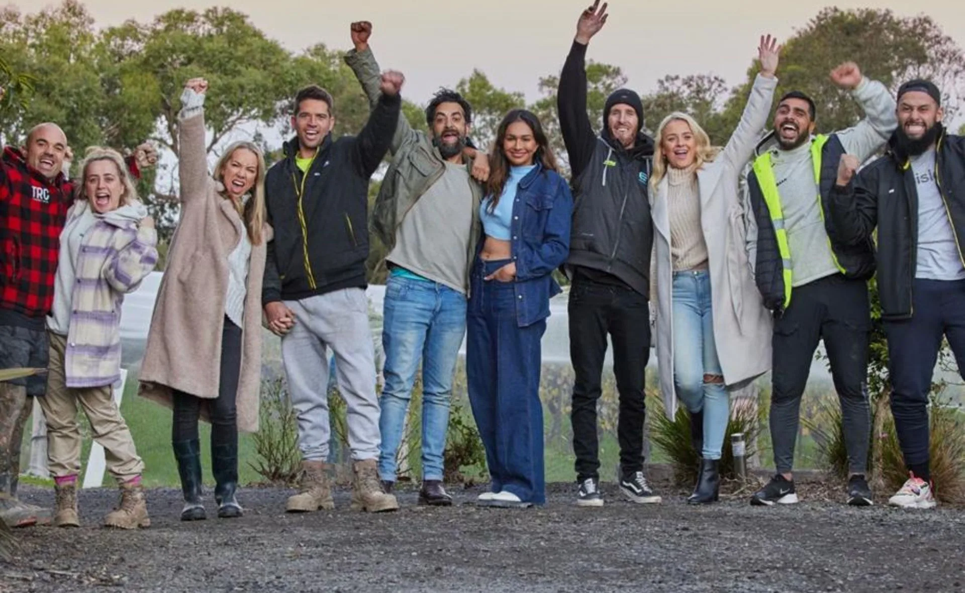 Group of people outdoors celebrating with raised fists and smiling faces, wearing casual and warm clothing.