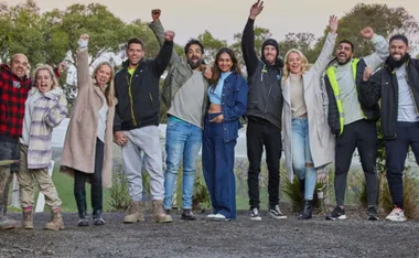 Group of people outdoors celebrating with raised fists and smiling faces, wearing casual and warm clothing.