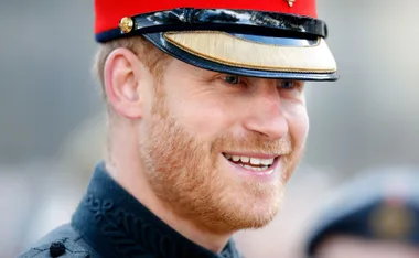 A person in a red military uniform cap smiling brightly.