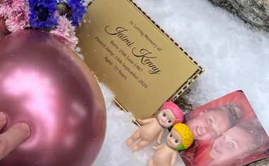 Plaque for Jaimi Kenny with flowers, a pink balloon, two figurines, and a photo on snow.