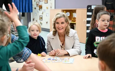Sophie, Countess of Wessex, wearing a white coat, engages with children at a table filled with cards and activity materials.