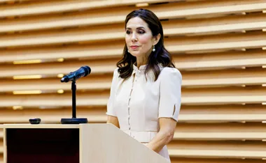 Princess Mary speaking at a podium with a microphone, wearing a light-colored dress.